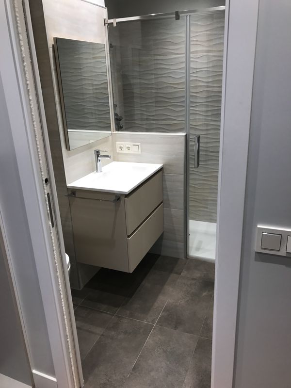 Baño reformado con mueble de lavabo suspendido y ducha