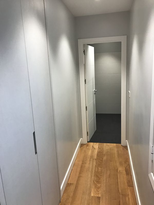 Pasillo con parquet y rodapié blanco